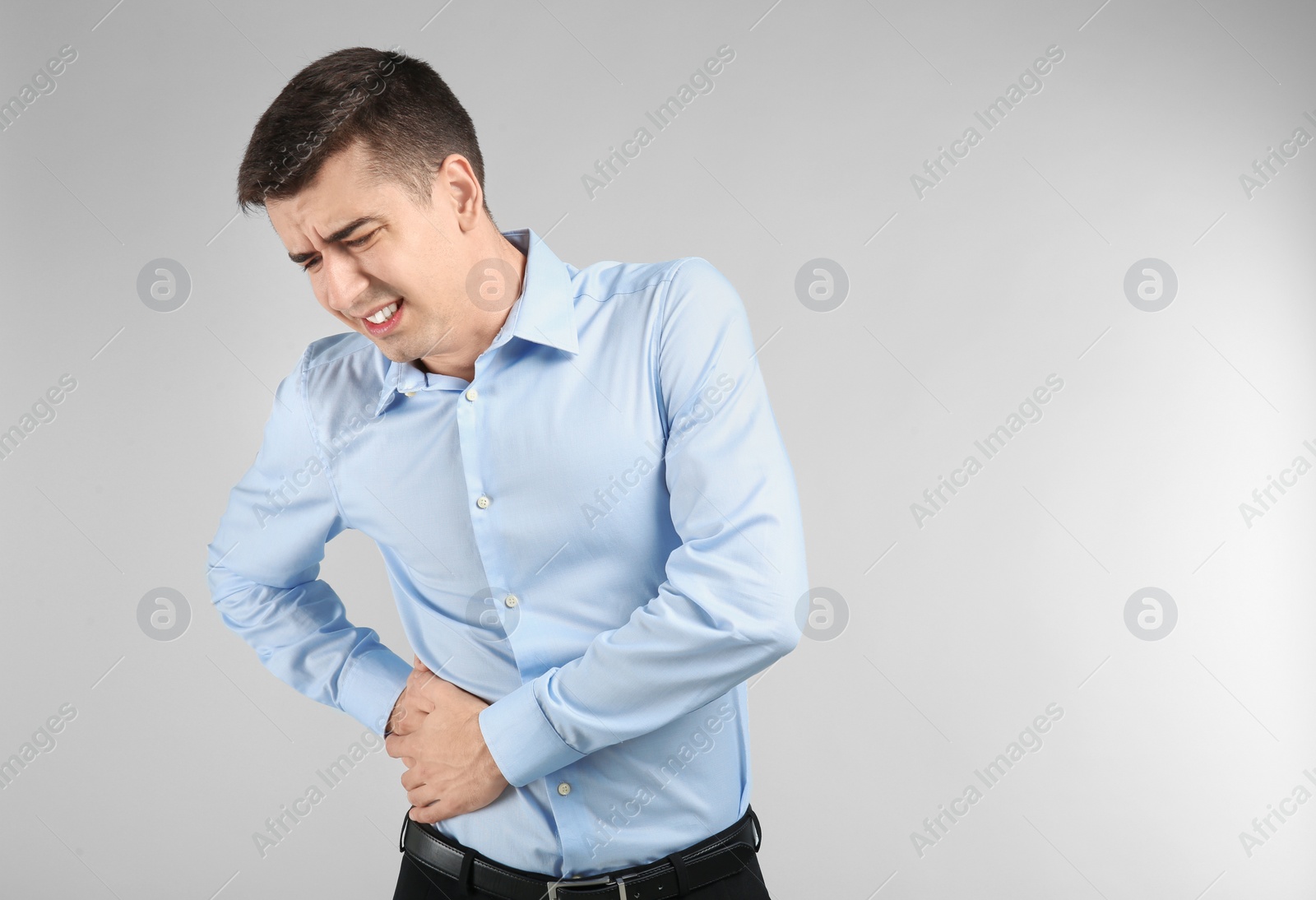 Photo of Young man suffering from flank pain on light background