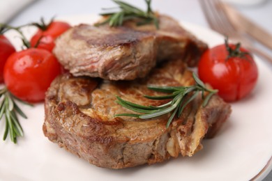 Photo of Delicious fried meat with rosemary and tomatoes on plate, closeup