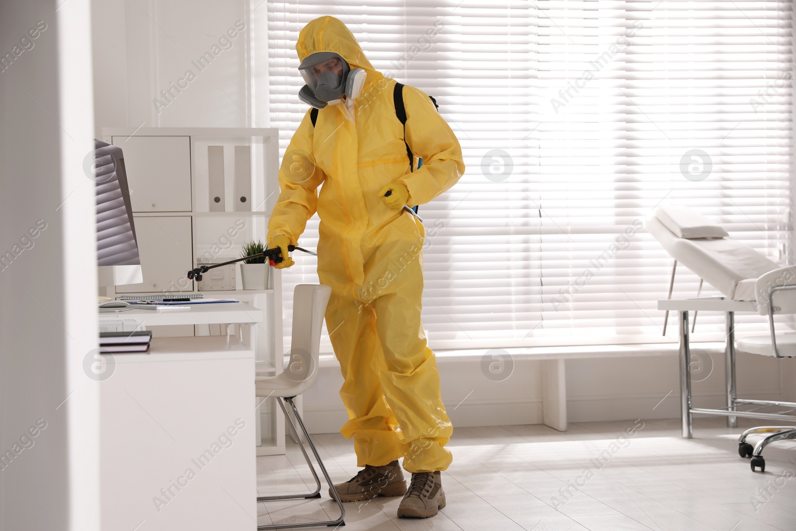 Photo of Man in protective suit sanitizing doctor's office. Medical disinfection