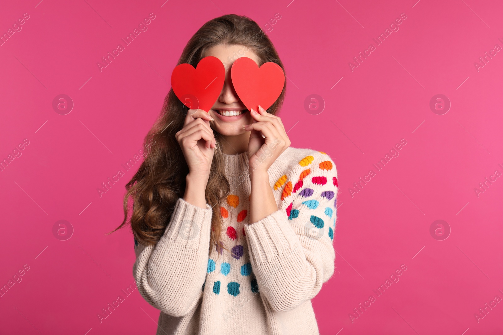 Photo of Portrait of young woman holding paper hearts near eyes on color background