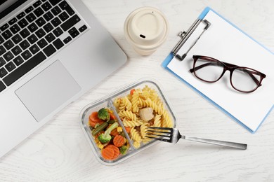 Container of tasty food, fork, laptop, paper cup of coffee and clipboard on white wooden table, flat lay. Business lunch