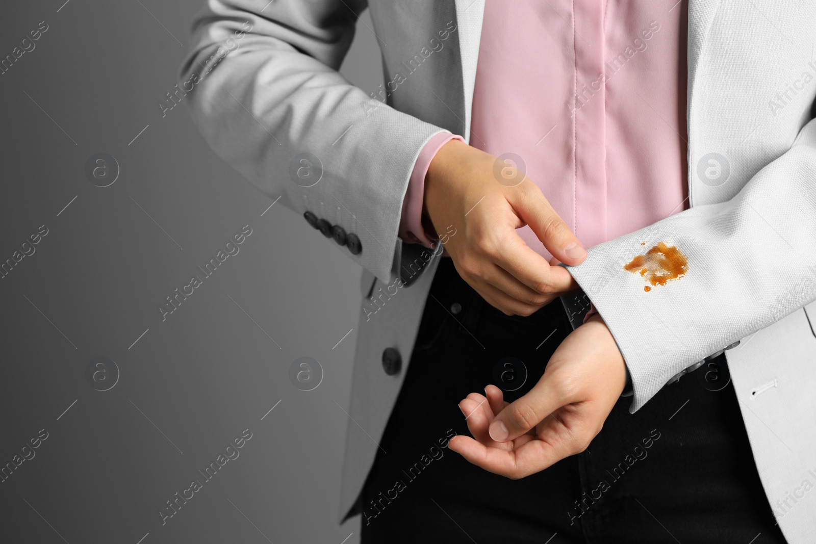 Photo of Woman showing stain of coffee on her jacket against grey background, closeup. Space for text