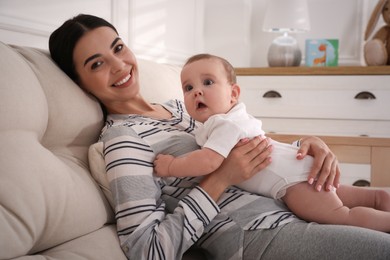 Photo of Young mother with her little baby on sofa at home