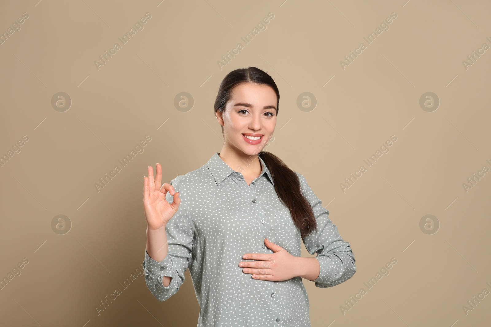 Photo of Happy healthy woman touching her belly on beige background