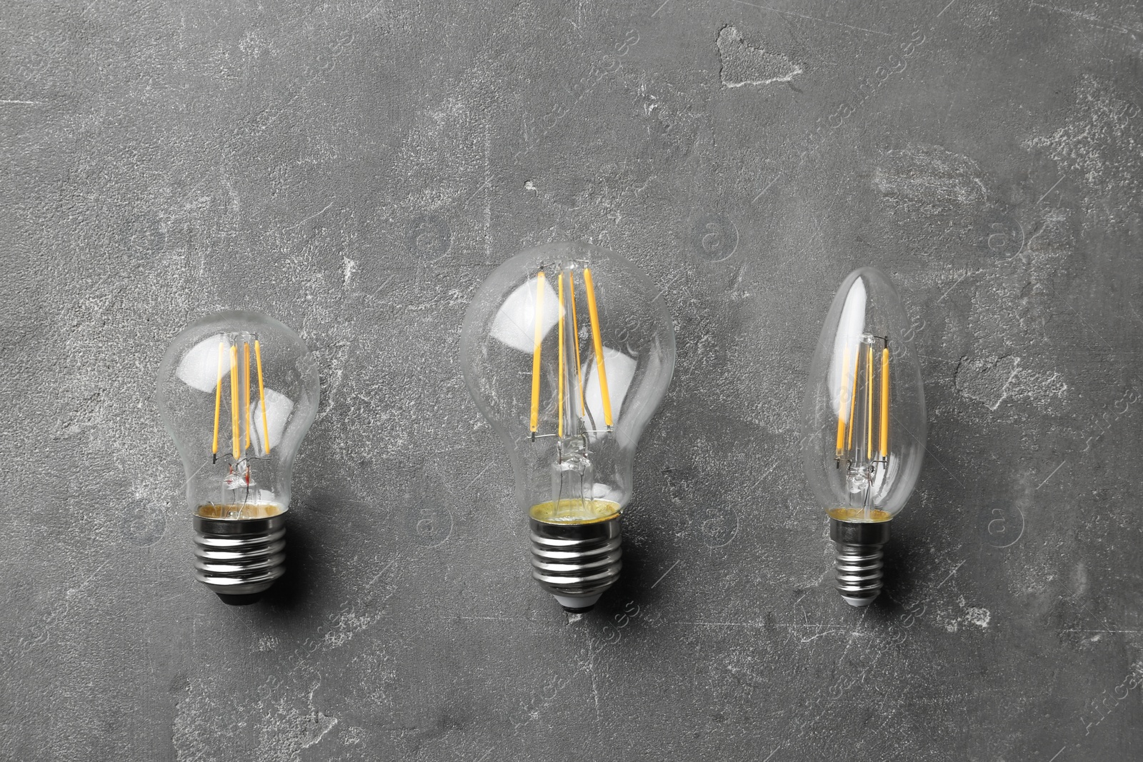Photo of New vintage lamp bulbs on grey stone surface, flat lay
