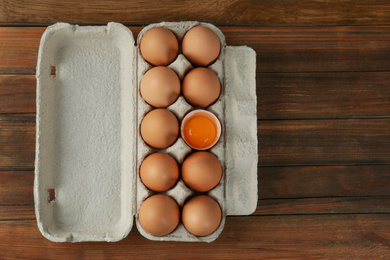 Photo of Raw chicken eggs on wooden table, top view