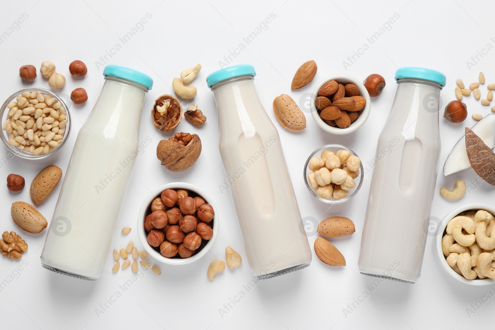 Photo of Vegan milk and different nuts on white background, flat lay