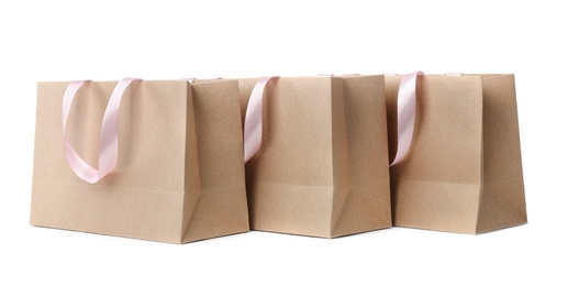 Paper shopping bags with ribbon handles on white background. Mockup for design