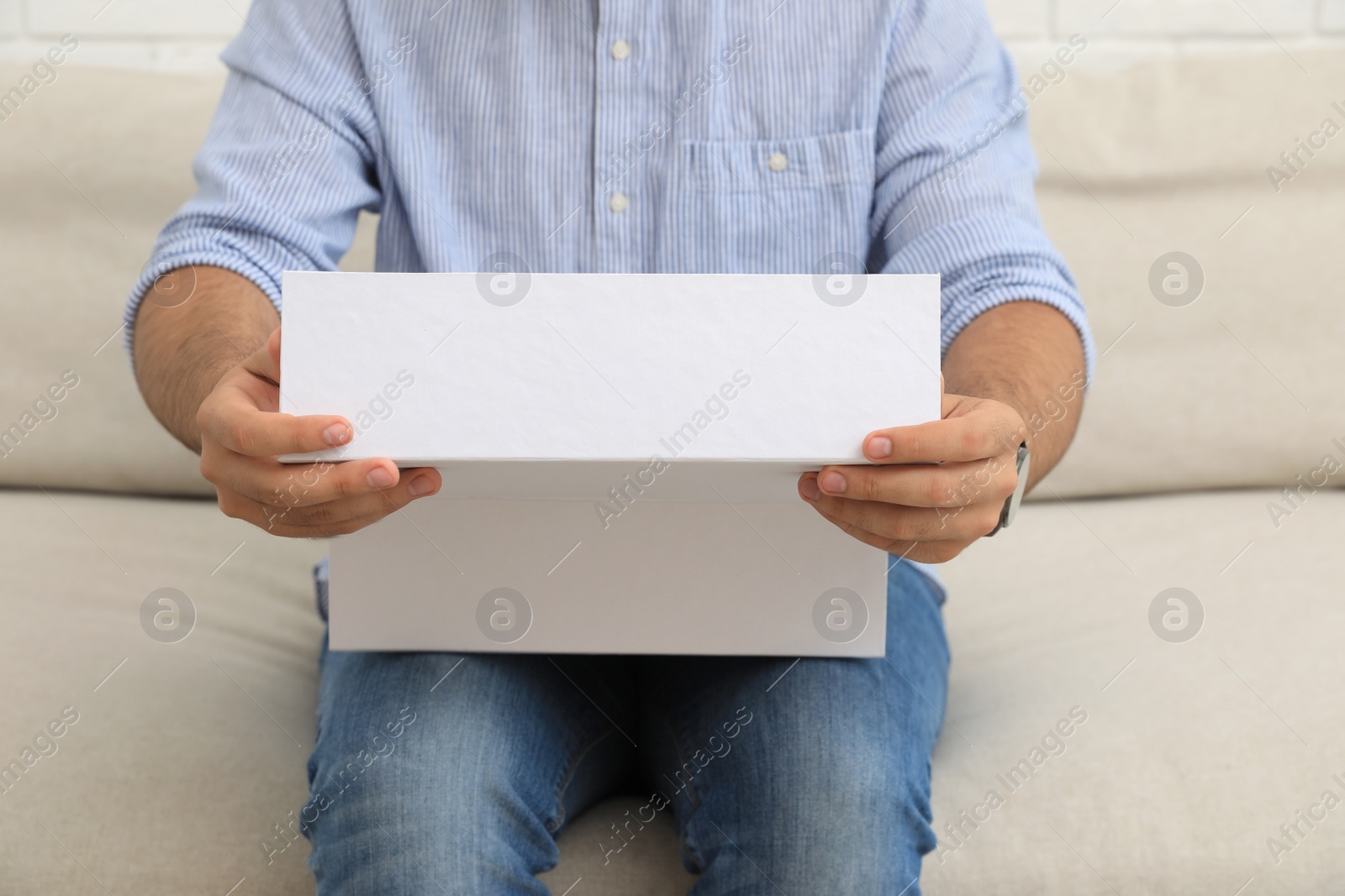 Photo of Man unpacking parcel at home, closeup. Online shopping