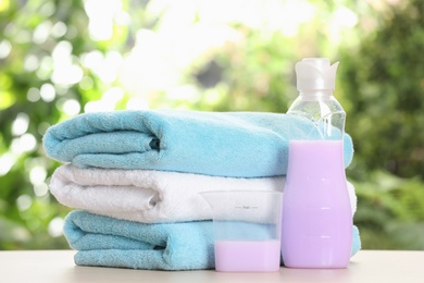 Photo of Soft bath towels and laundry detergent on table against blurred background