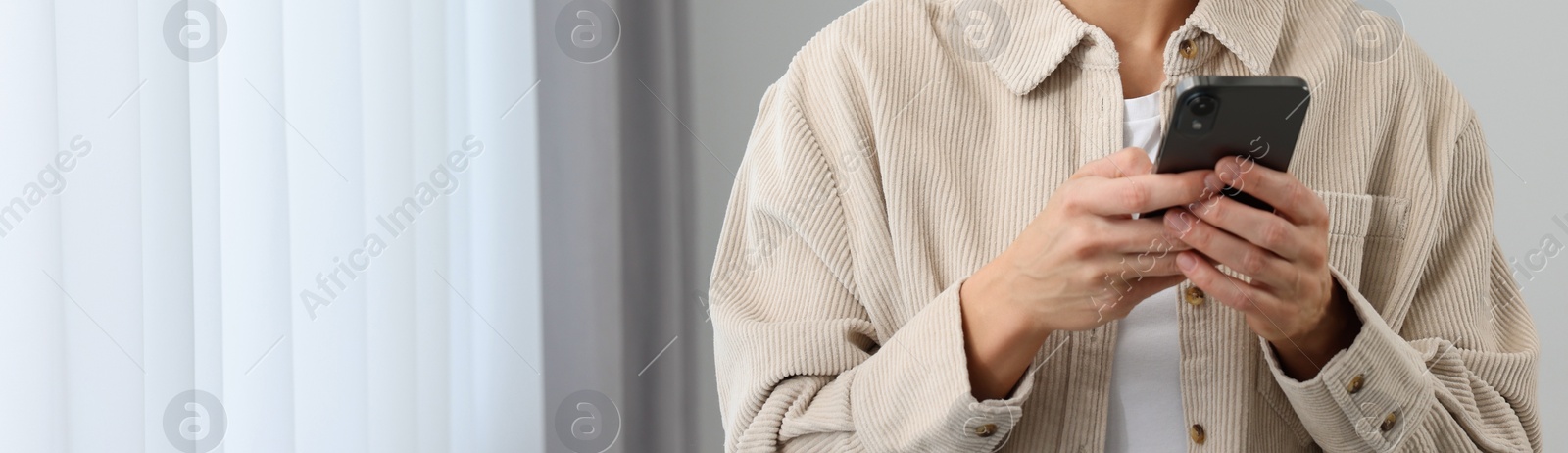 Image of Woman typing message on mobile phone indoors, closeup. Banner design with space for text