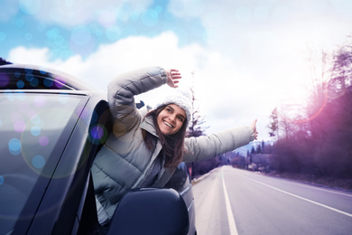 Image of Happy woman leaning out of car window on road. Winter vacation