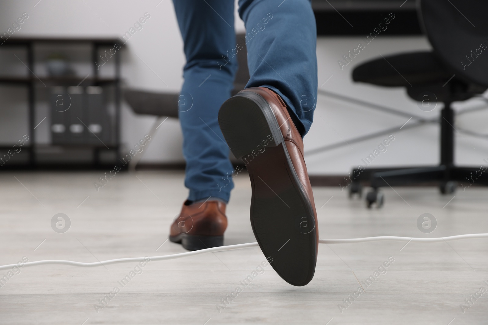 Photo of Man tripping over cord in office, closeup