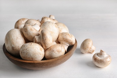 Photo of Bowl with fresh champignon mushrooms on wooden table. Space for text