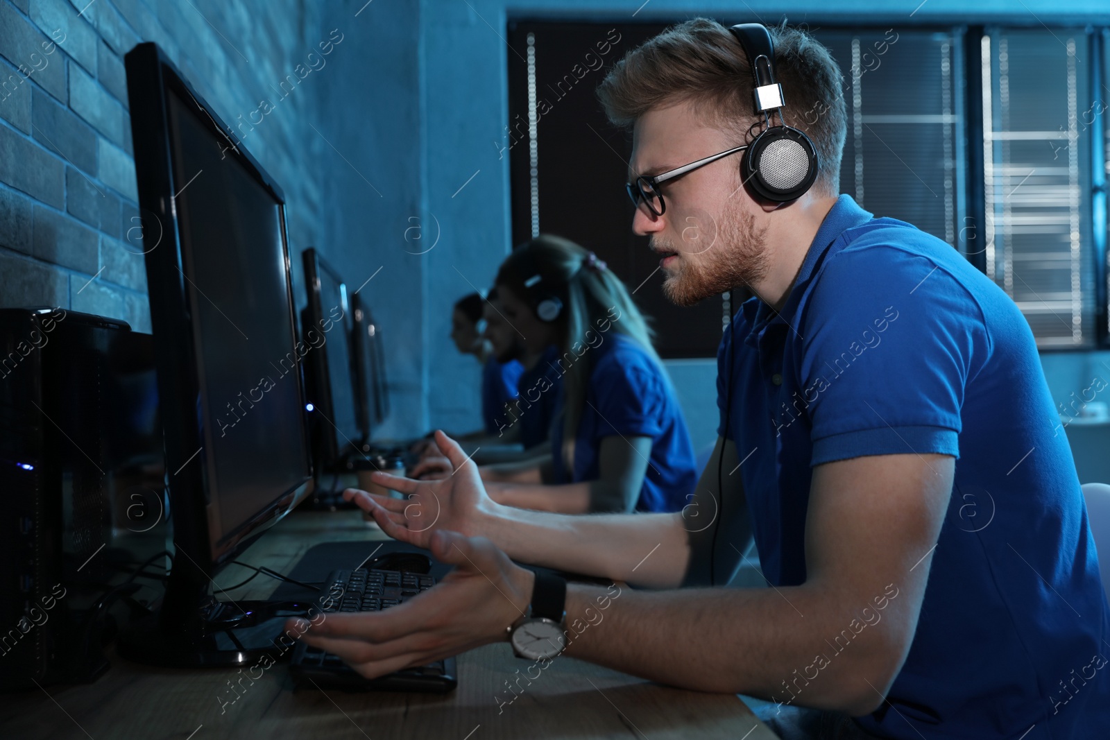 Photo of Emotional man playing video game in internet cafe