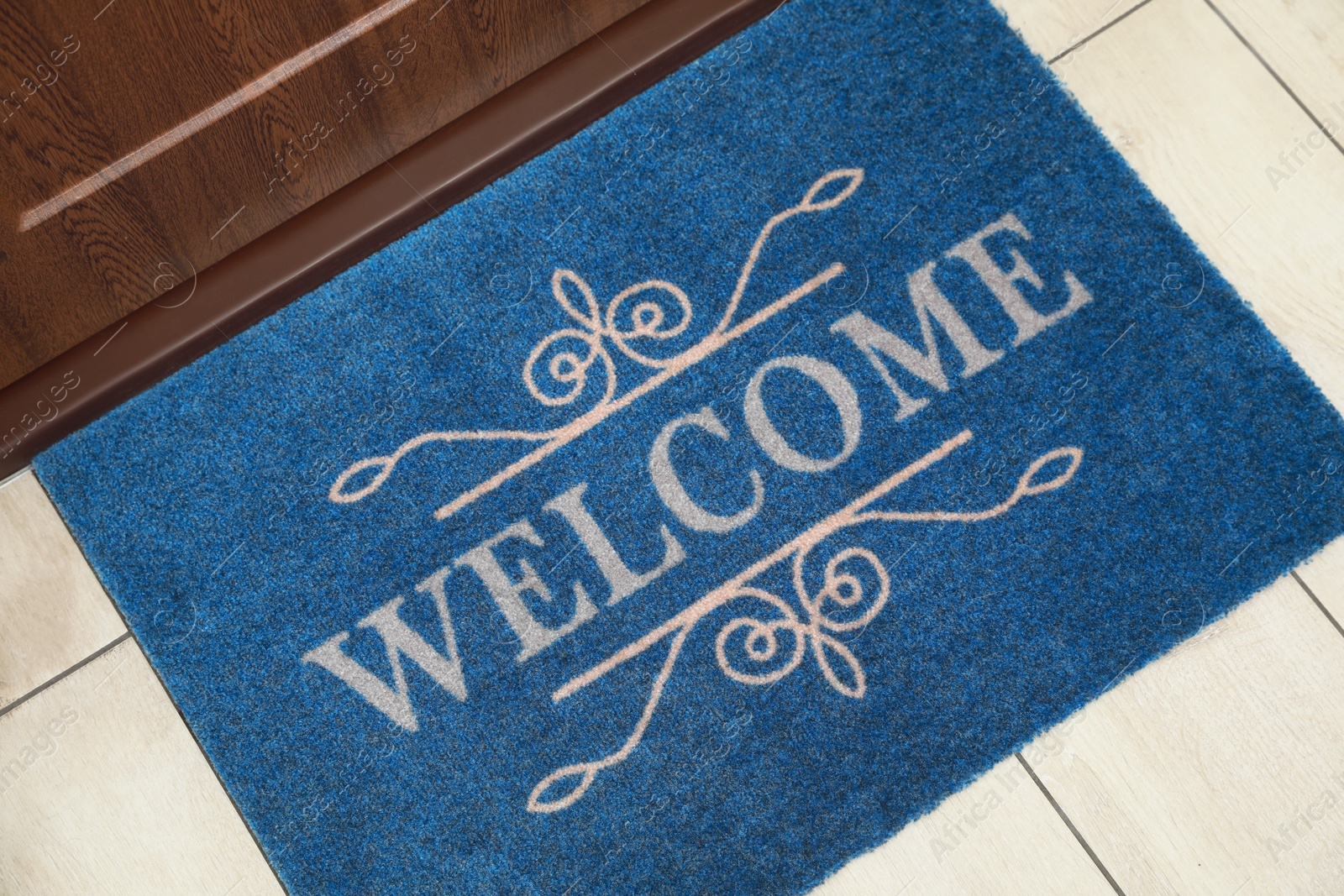 Photo of Beautiful blue doormat with word Welcome on floor near entrance, above view