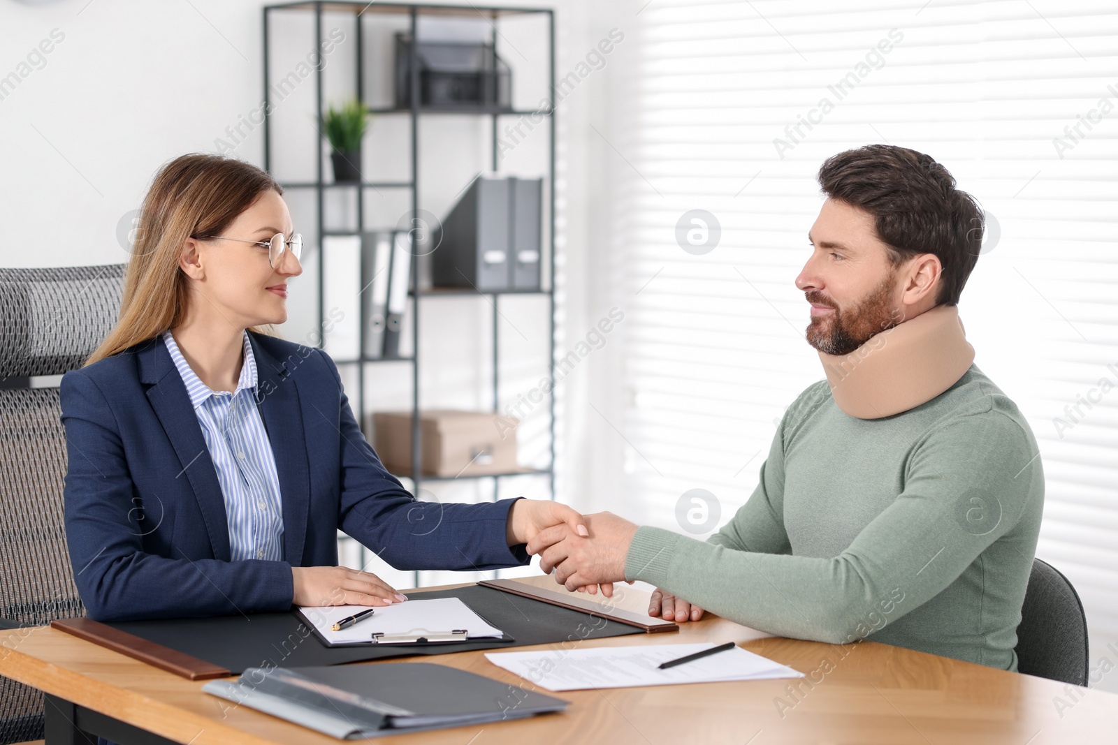 Photo of Lawyer shaking hands with injured client in office