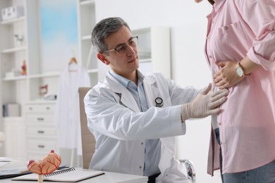 Gastroenterologist examining patient with stomach pain in clinic