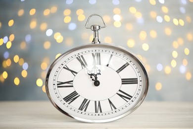 Photo of Clock showing five minutes until midnight on blurred background. New Year countdown