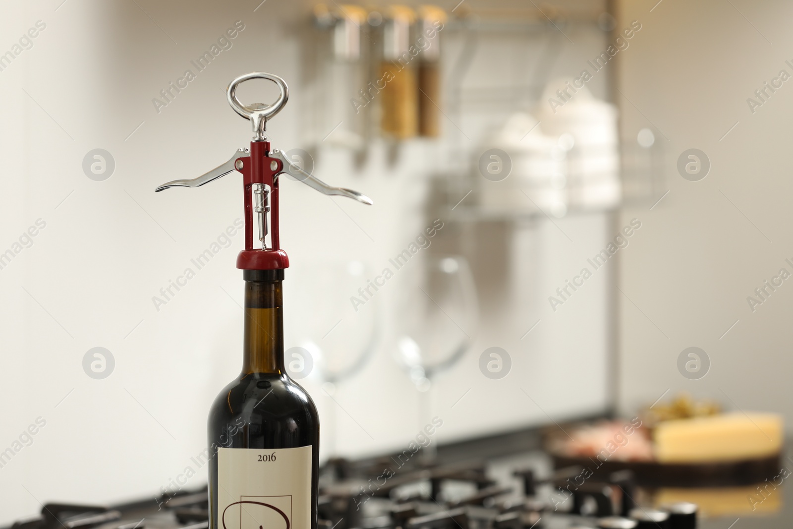 Photo of Wine bottle with metal corkscrew in kitchen. Space for text