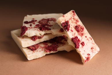 Photo of White chocolate with freeze dried raspberries on brown table, closeup