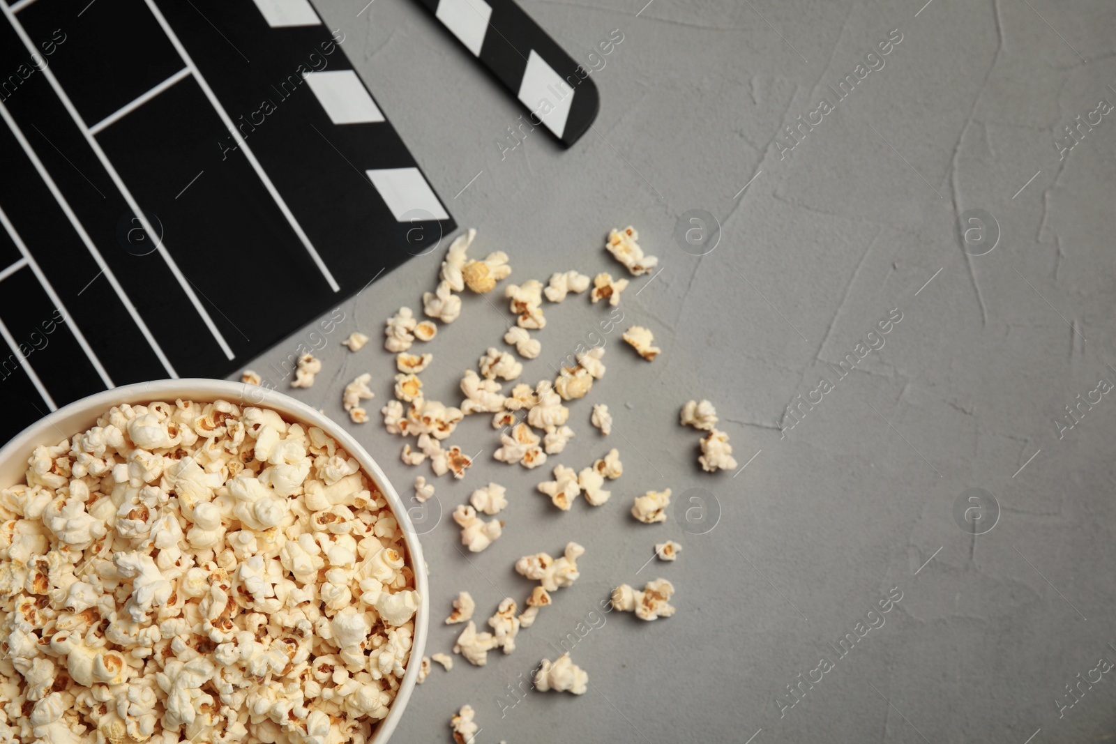 Photo of Flat lay composition with popcorn and clapperboard on grey background