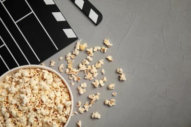 Flat lay composition with popcorn and clapperboard on grey background