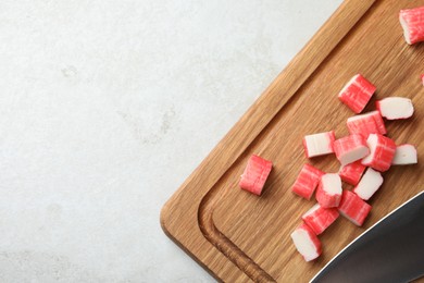 Board with cut crab sticks on light table, top view. Space for text