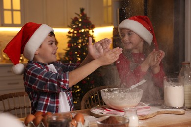 Photo of Happy little children having fun while making dough for Christmas cookies at home