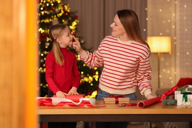 Photo of Christmas presents wrapping. Mother and her little daughter decorating gift boxes at home