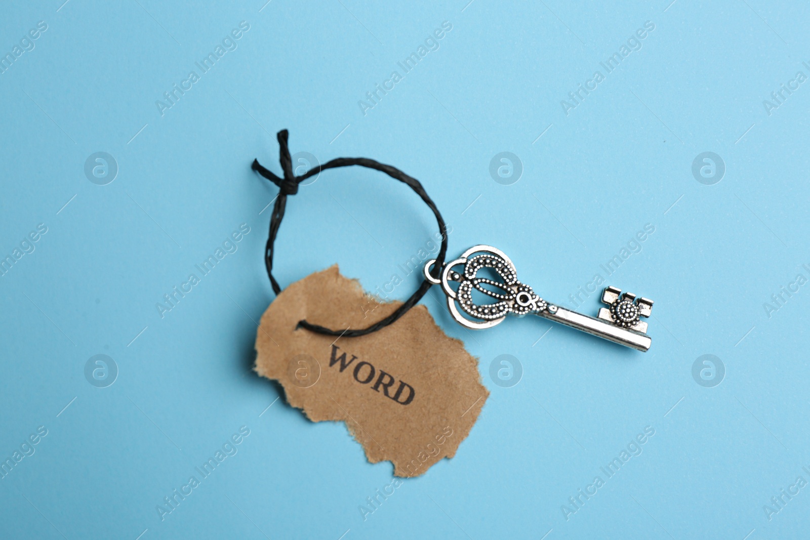 Photo of Vintage key with tag on light blue background, top view. Keyword concept