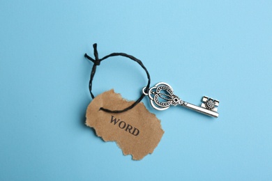 Vintage key with tag on light blue background, top view. Keyword concept