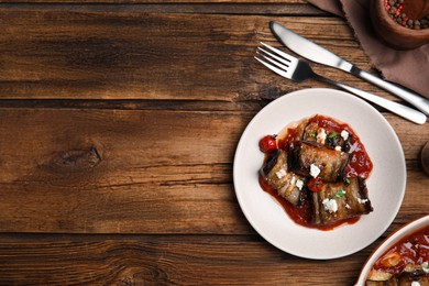 Tasty eggplant rolls served on wooden table, flat lay. Space for text