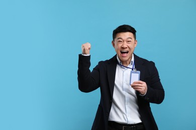 Photo of Excited asian man with vip pass badge on light blue background. Space for text