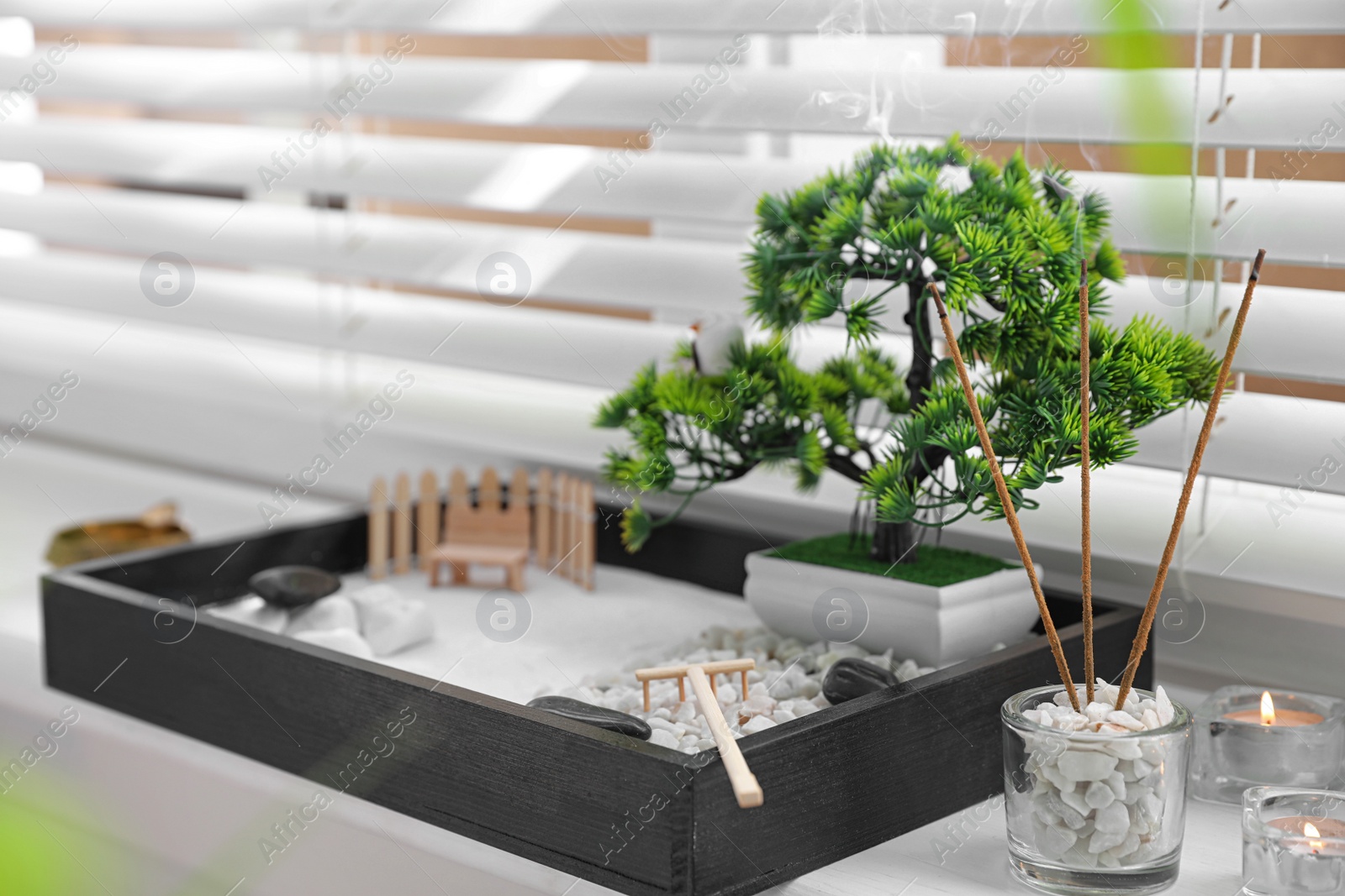 Photo of Beautiful miniature zen garden, candles and incense sticks on window sill