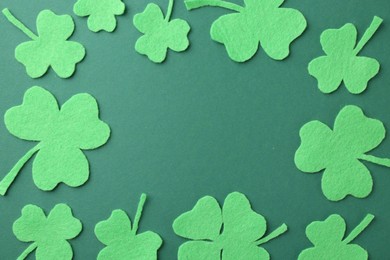 Photo of St. Patrick's day. Frame of decorative clover leaves on green background, flat lay. Space for text
