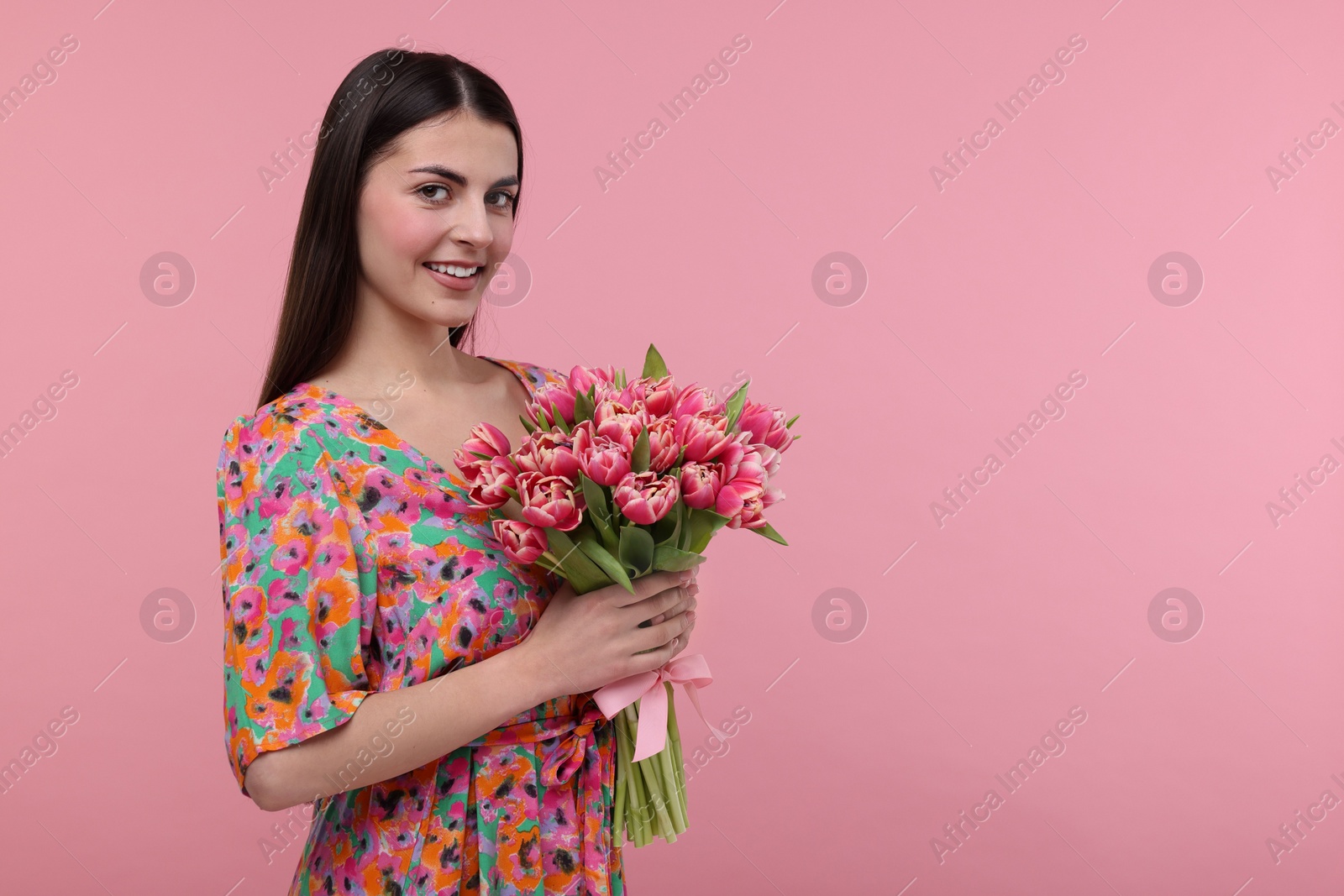 Photo of Happy young woman with beautiful bouquet on dusty pink background. Space for text