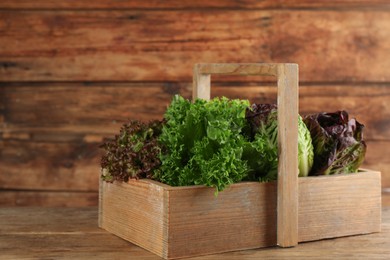Crate with different sorts of lettuce on wooden table