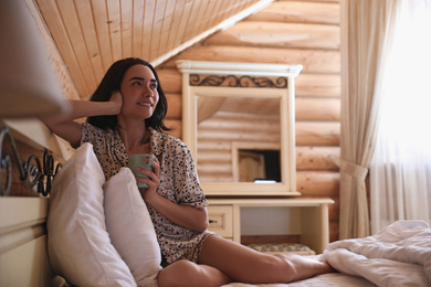 Young woman in pajamas with drink on bed at home. Lazy morning