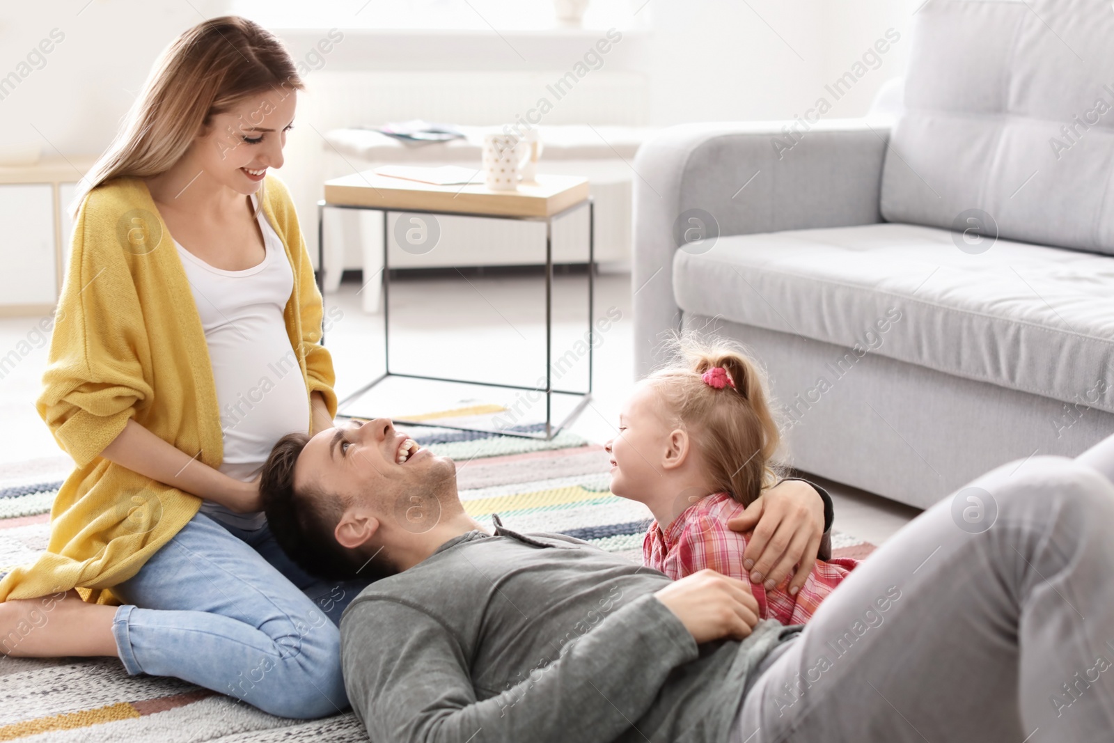 Photo of Young pregnant woman with her family at home