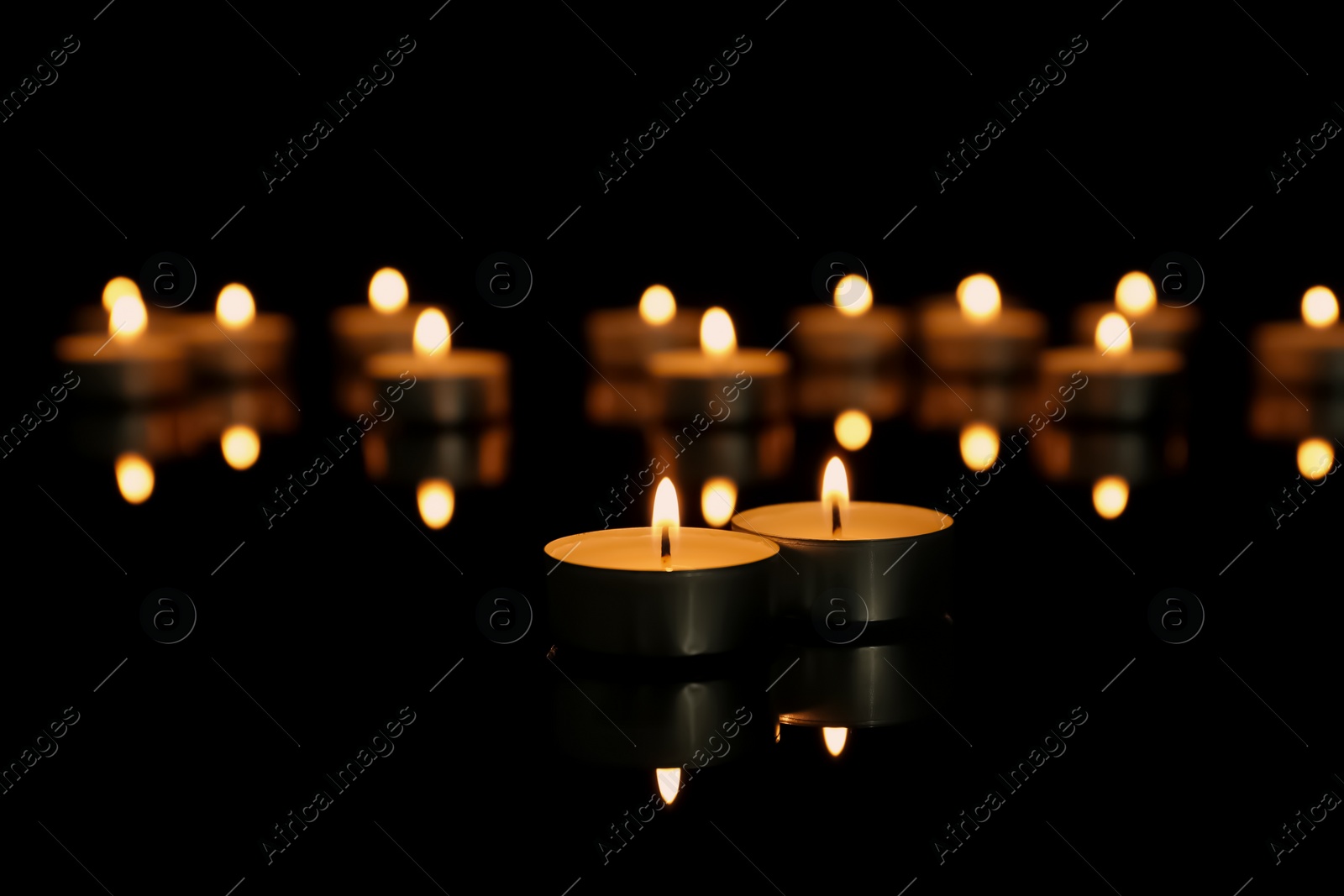 Photo of Burning candles on table against dark background