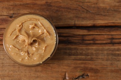 Delicious nut butter in bowl on wooden table, top view. Space for text