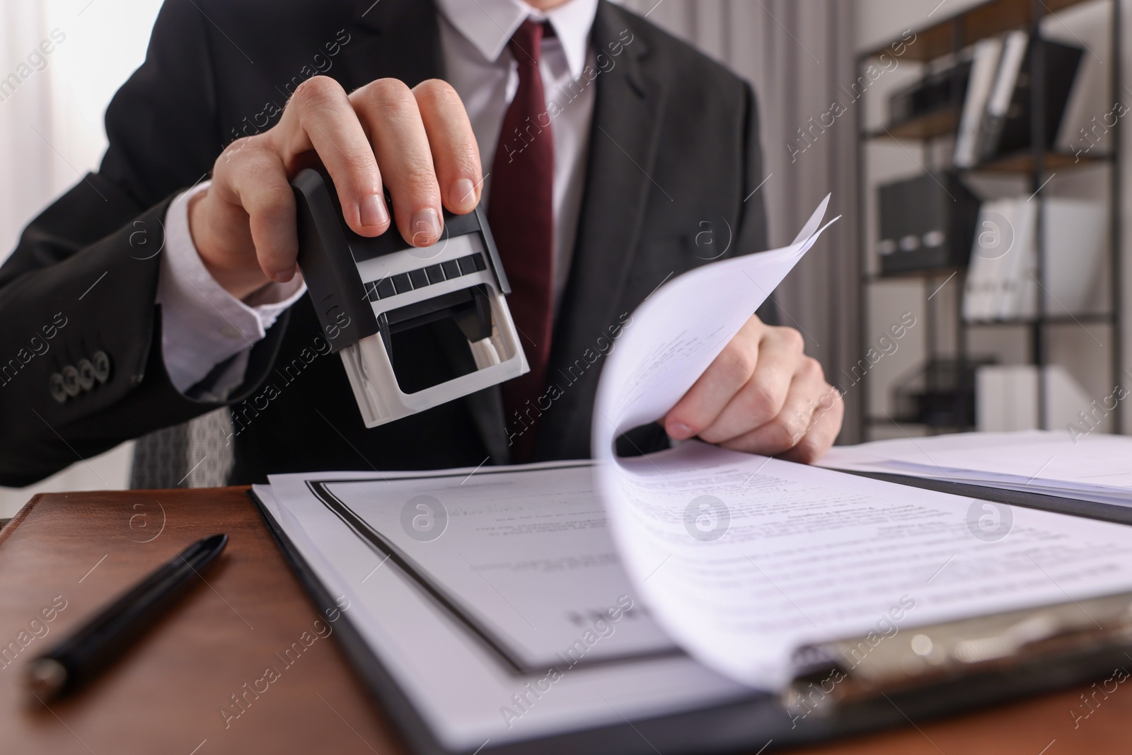 Photo of Notary stamping document at table in office, low angle view