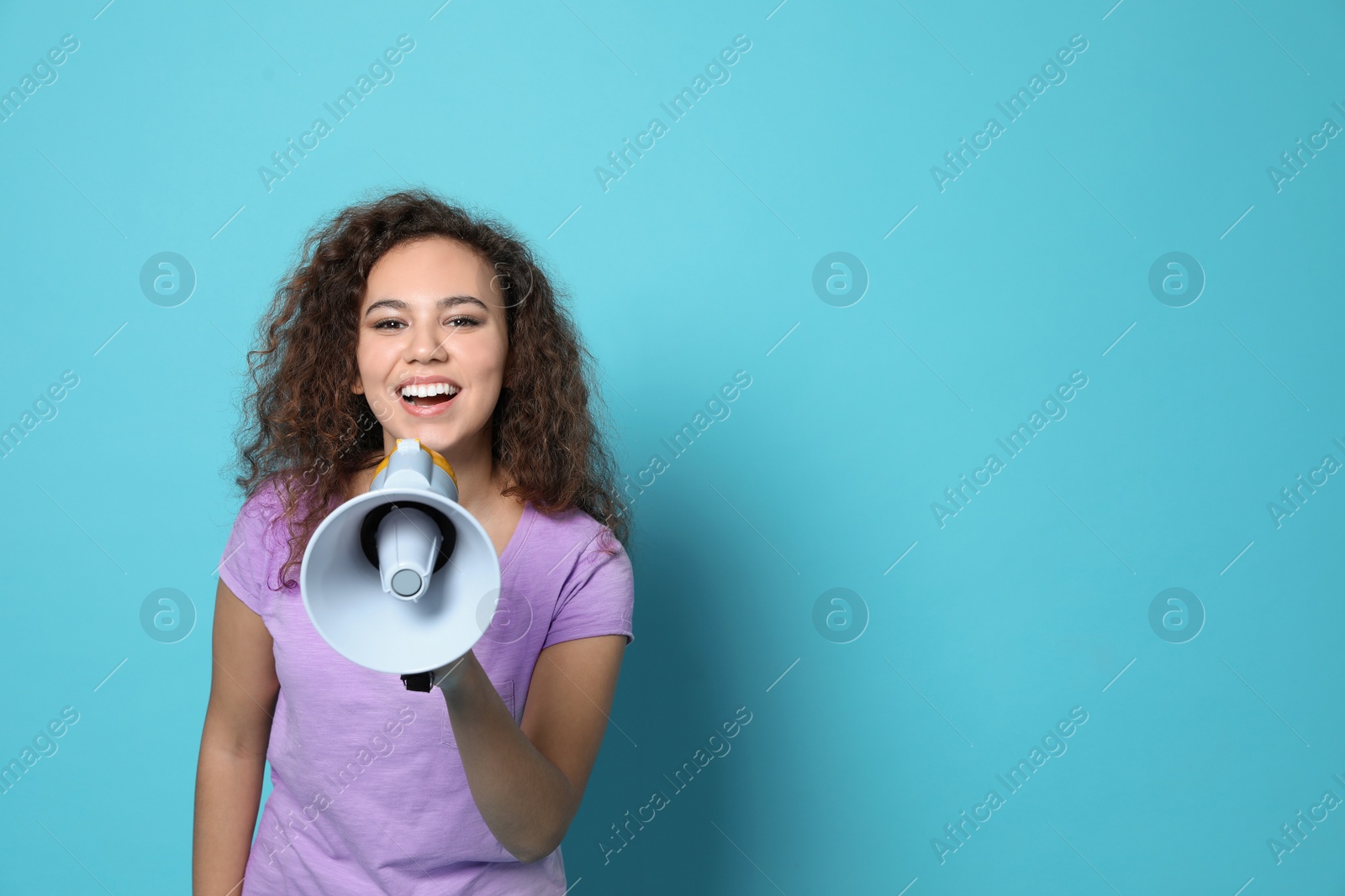 Photo of Young African-American woman with megaphone on color background. Space for text