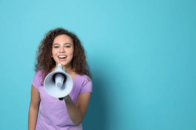 Young African-American woman with megaphone on color background. Space for text