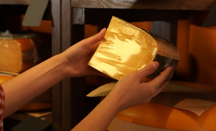 Woman choosing tasty cheese from display in store