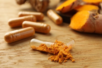 Aromatic turmeric powder and pills on wooden table, closeup