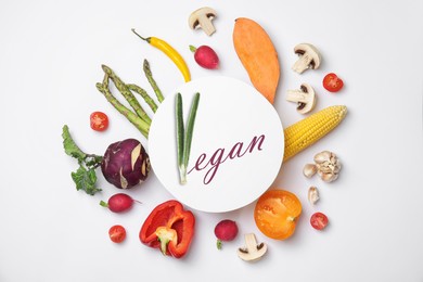 Image of Paper card with word Vegan and fresh vegetables on white background, flat lay