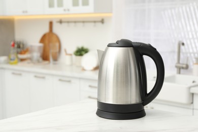 Photo of Modern electric kettle on table in kitchen. Space for text