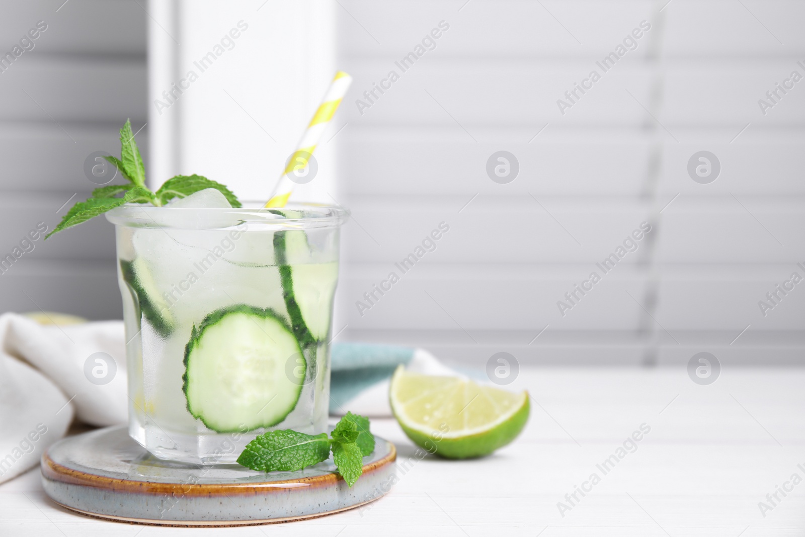 Photo of Glass of refreshing cucumber water with mint on white wooden table, space for text